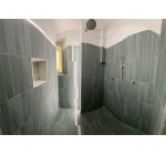 Dettaglio doccia walk-in con rivestimenti in gres moderno e nicchia portaoggetti illuminata a Casa Pontano.