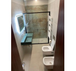 Bagno completo ad uso esclusivo della seconda camera matrimoniale: lavabo moderno e doccia con rivestimento d'effetto.